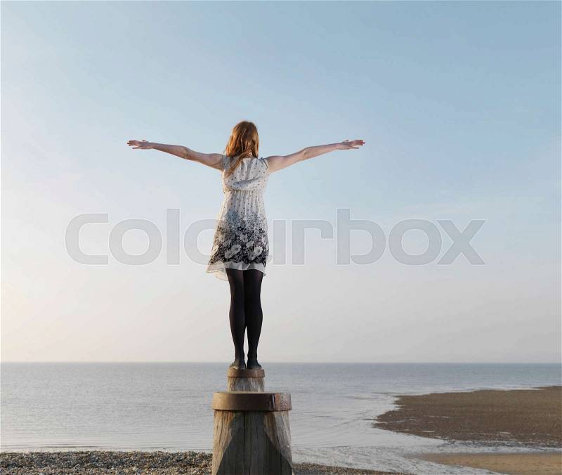 Woman balancing on wooden post, stock photo