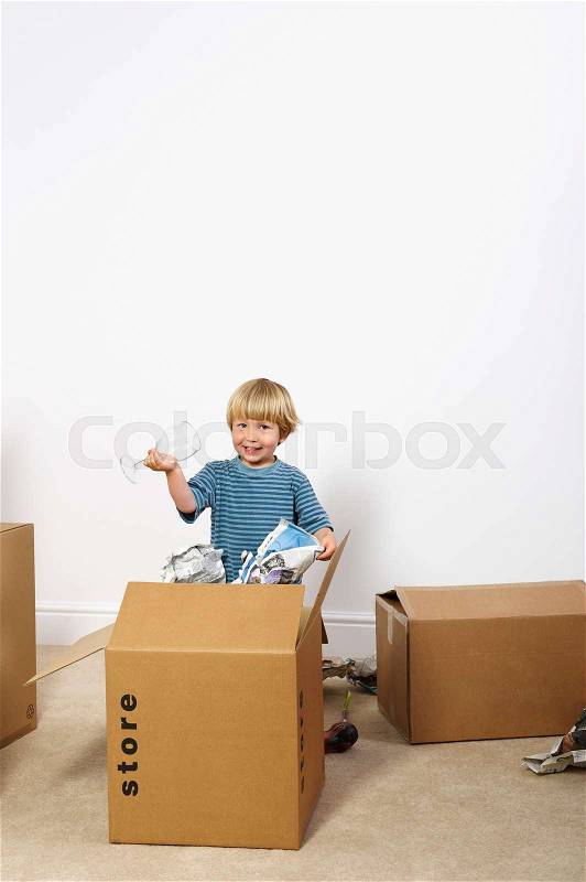 Boy unpacking glasses from box, stock photo