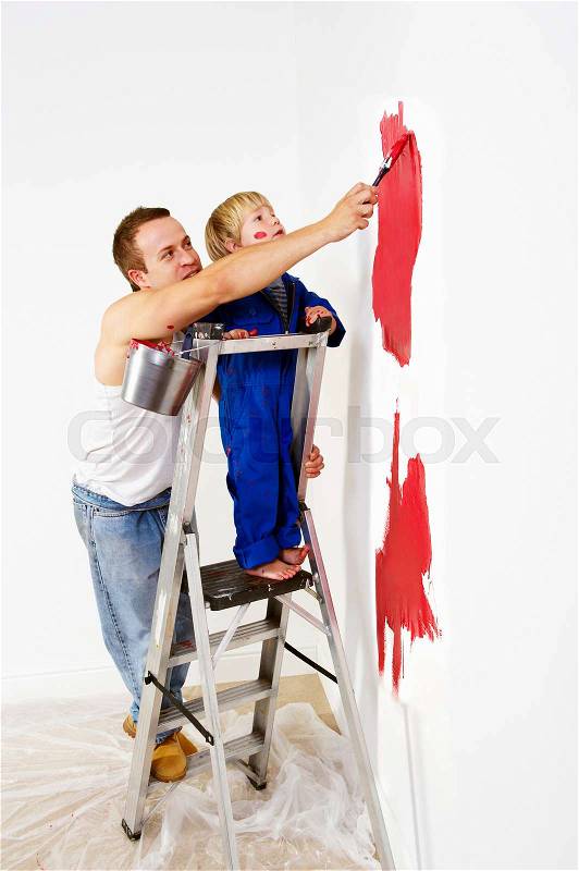 Man and toddler boy painting wall red, stock photo