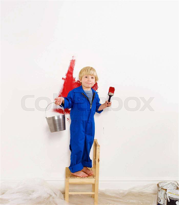 Toddler boy painting wall red, stock photo