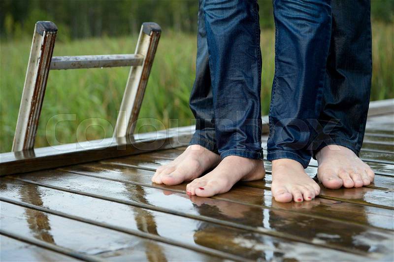 Wet feet of a couple on a dock, stock photo