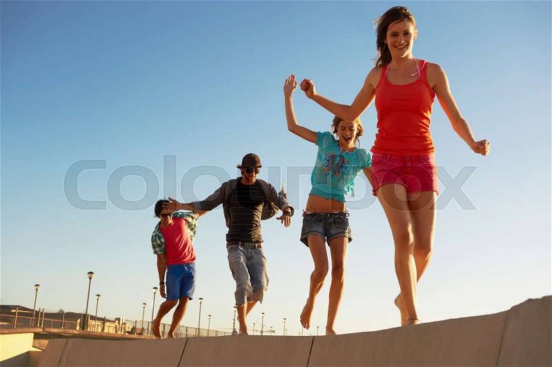Young people balancing on wall, stock photo