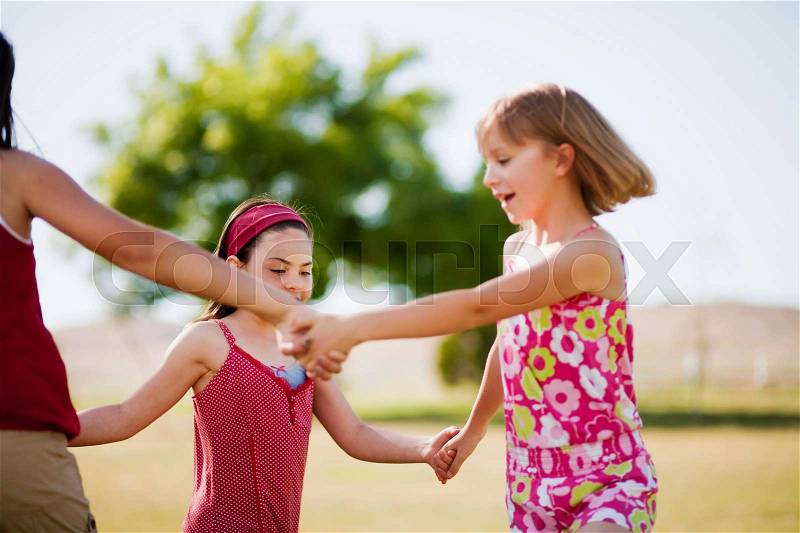 Girls holding hands dancing in a circle, stock photo