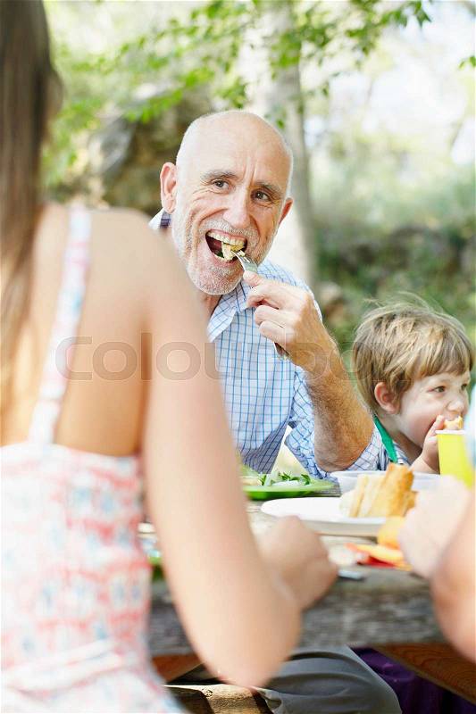 Older man eating at family picnic, stock photo