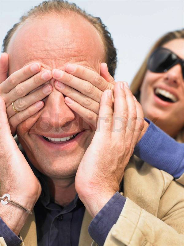 Woman hiding man\'s face with her hands, stock photo