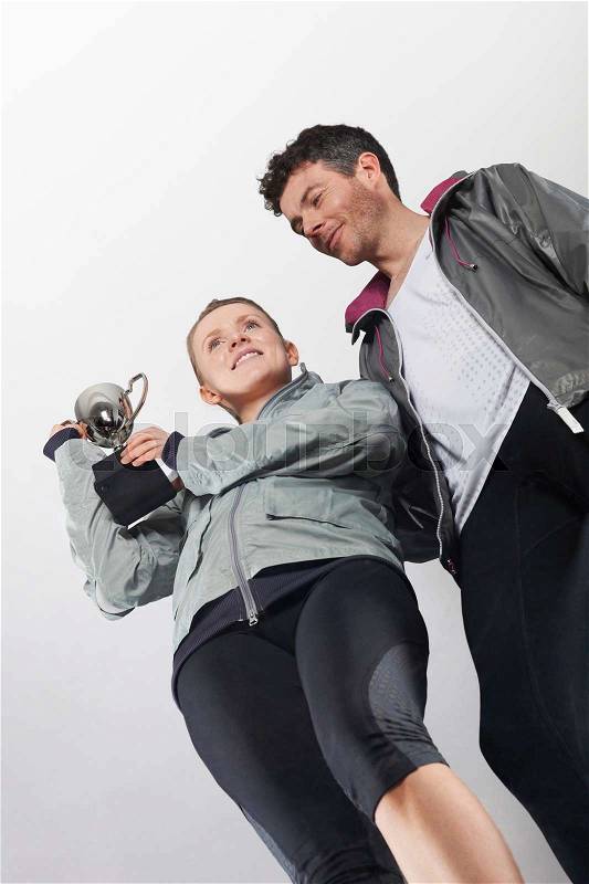 Couple in running gear holding trophy, stock photo