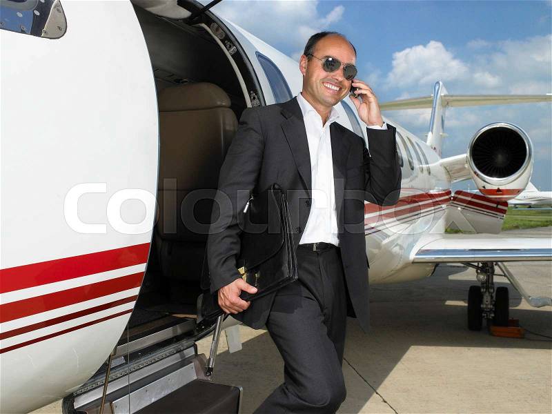 Smiling businessman exiting private jet, stock photo