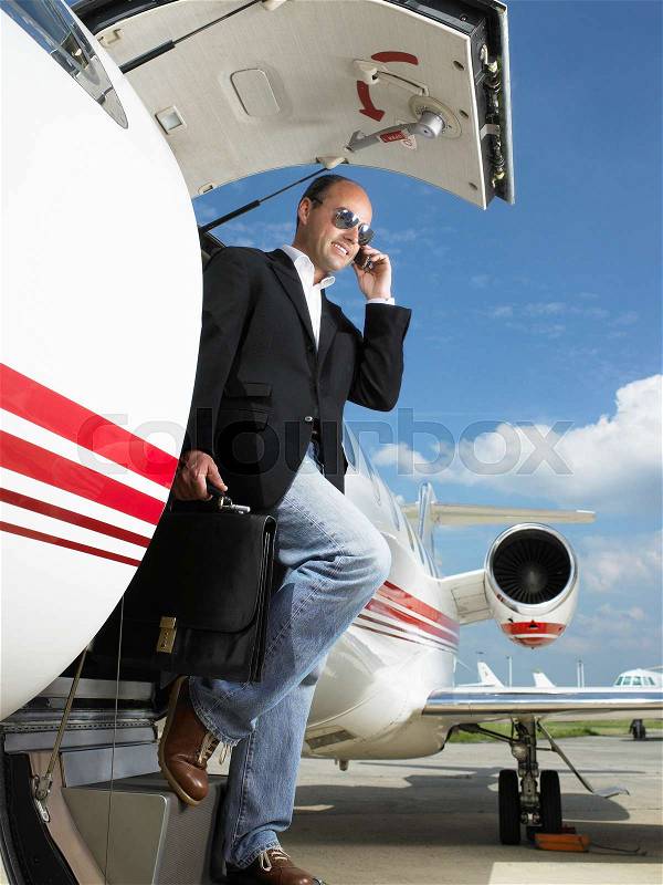 Casual businessman exiting private plane, stock photo