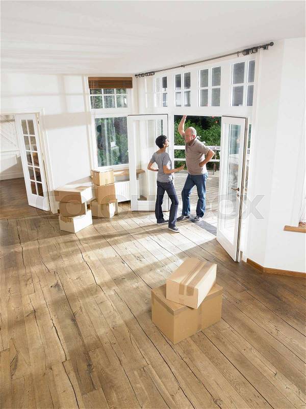 Couple moving boxes into empty house, stock photo
