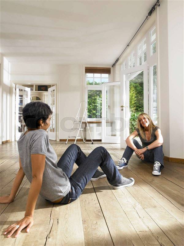 Two friends seated on floor, stock photo