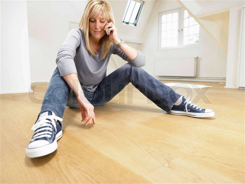 Relaxed woman seated on wooden floor, stock photo
