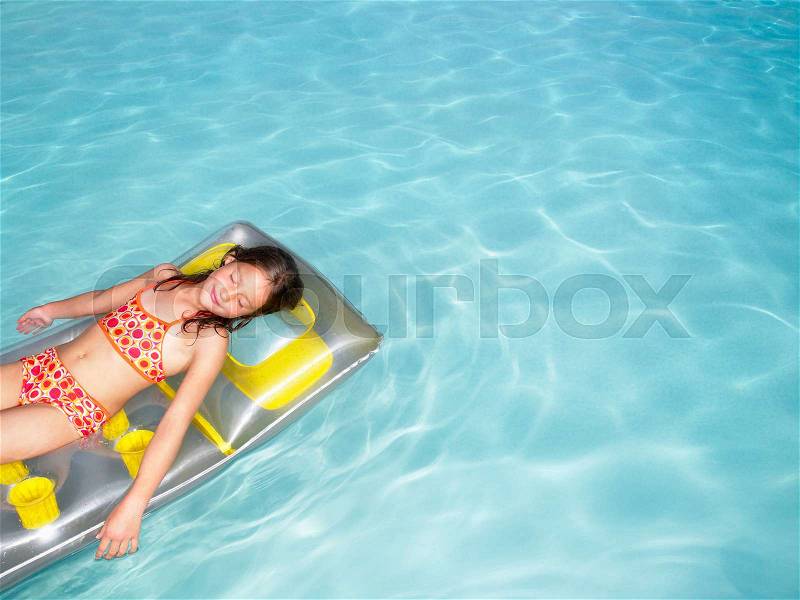 Girl on air mattress in pool, stock photo