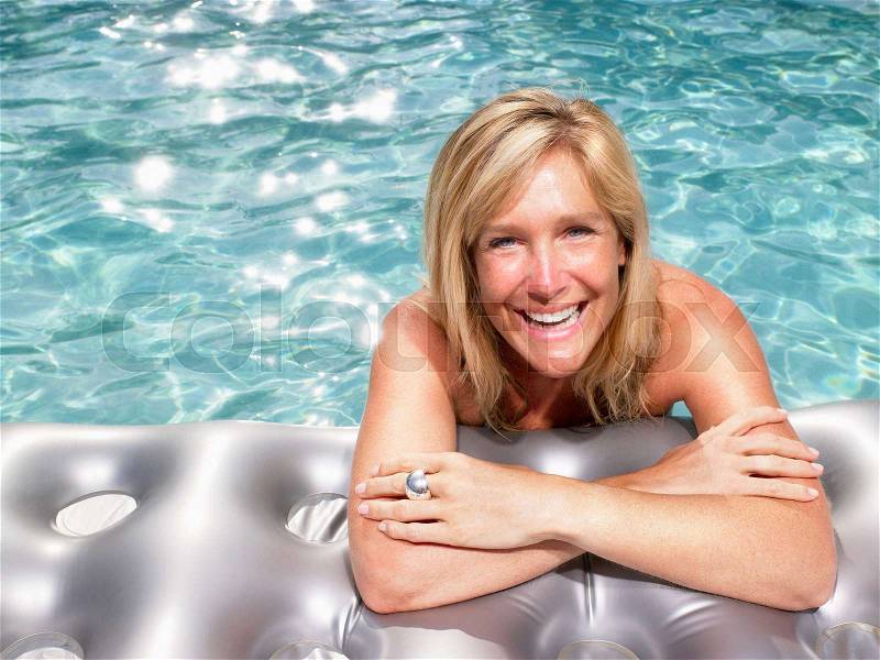 Woman on air mattress in pool, stock photo