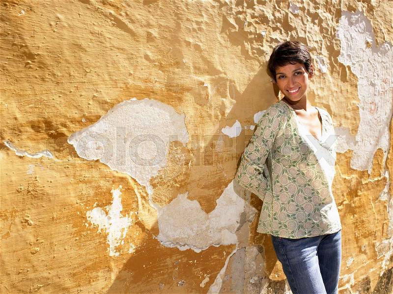 Woman standing up against a wall, stock photo