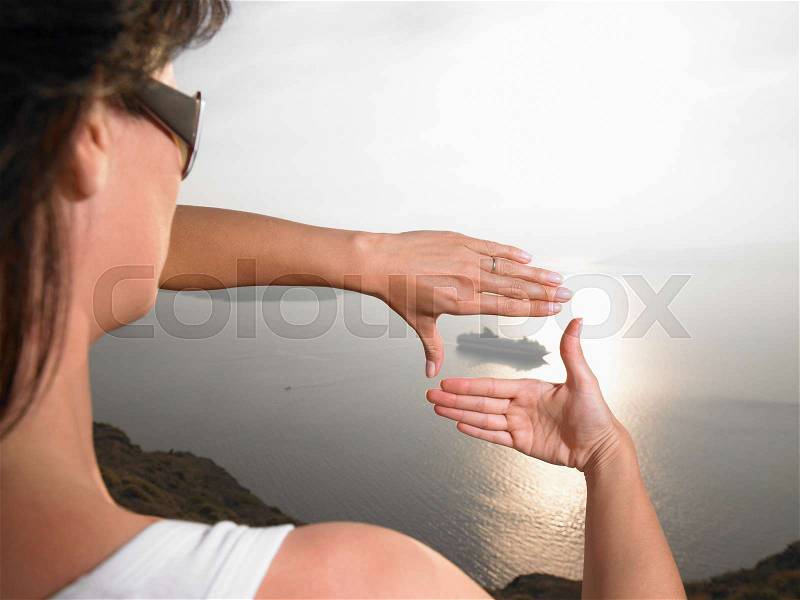 Woman framing a boat with her hands, stock photo