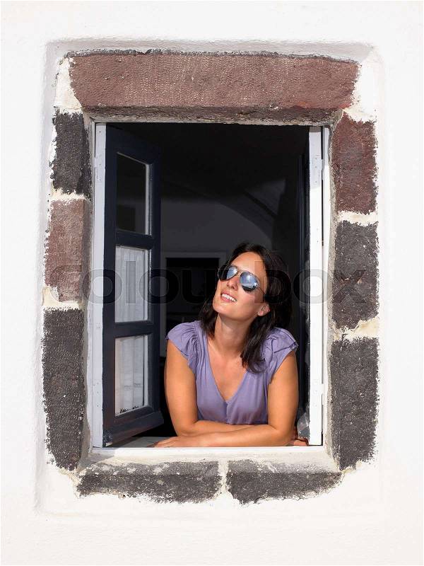 Woman looking through window, smiling, stock photo