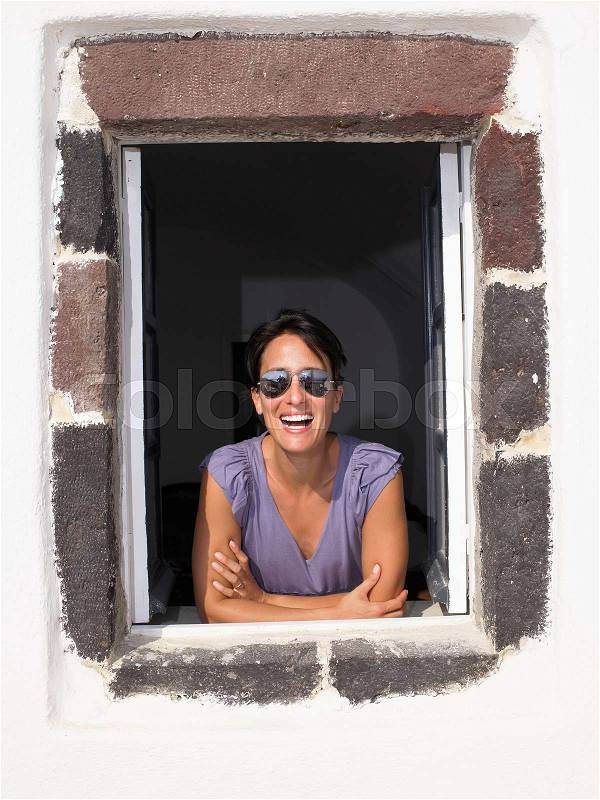 Woman looking through window, smiling, stock photo