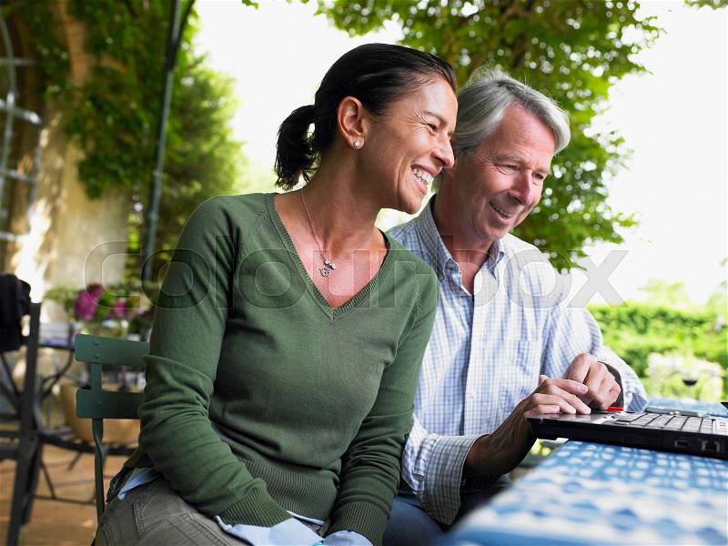 Couple on computer, laughing, stock photo