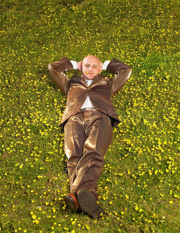Man lying on grass in gold suit, stock photo