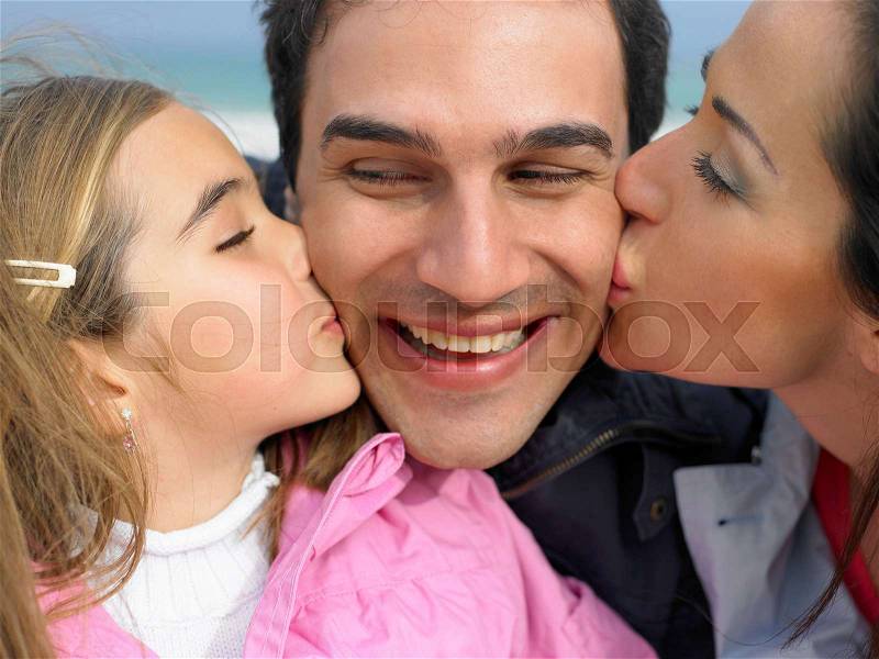Mother and daughter kissing father, stock photo