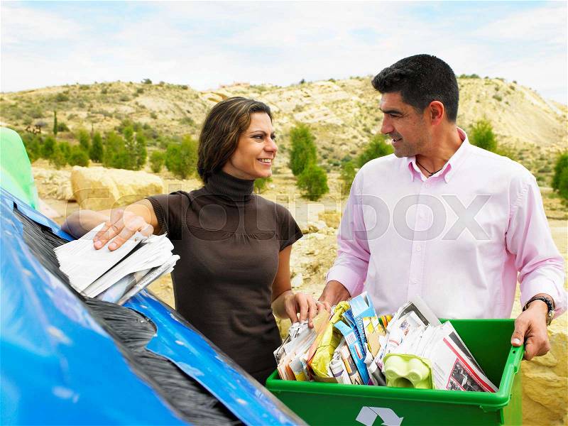Couple placing papers in a recycle bin, stock photo