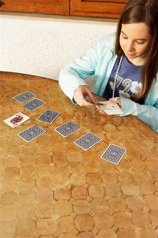 Girl playing cards on table, stock photo