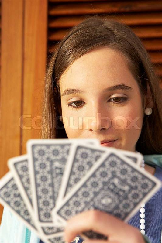 Girl holding playing card, stock photo