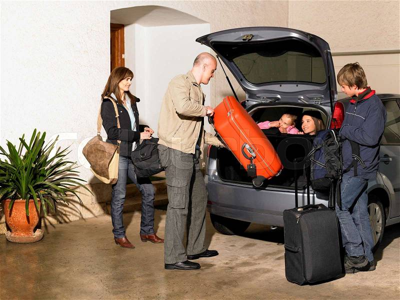 Family loading luggage into car on drive, stock photo
