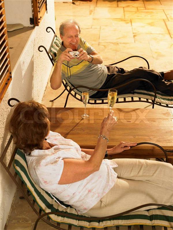 Senior couple lying on sun loungers, stock photo