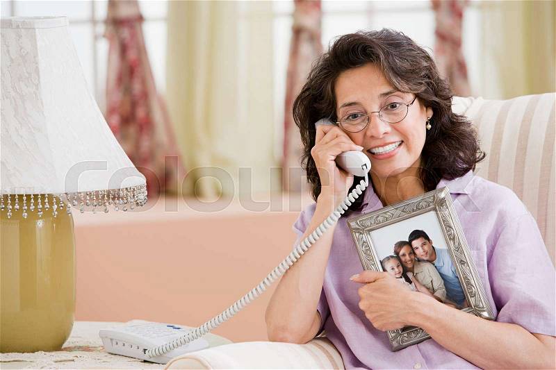 Woman on telephone with picture of family, stock photo