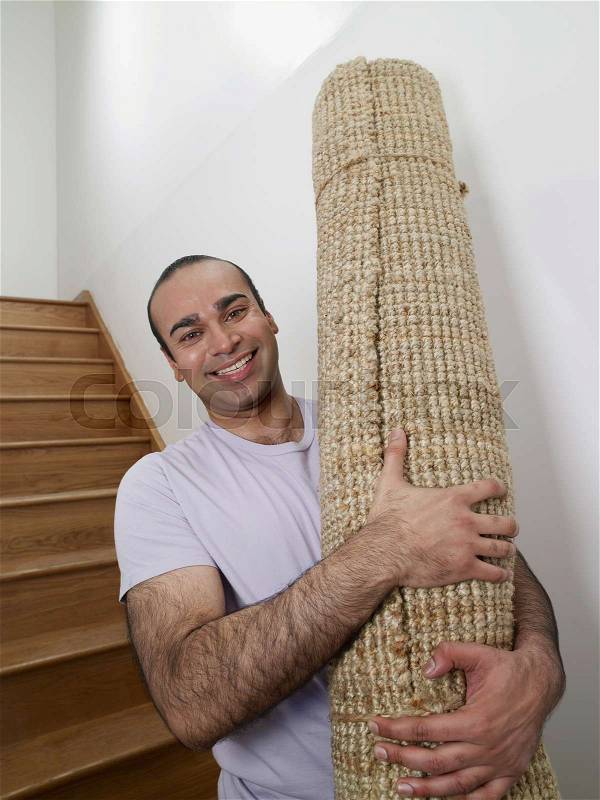 A man holding a rug in his new home, stock photo