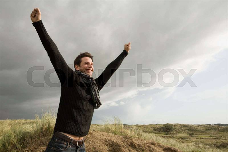 Man outdoors with arms raised, stock photo