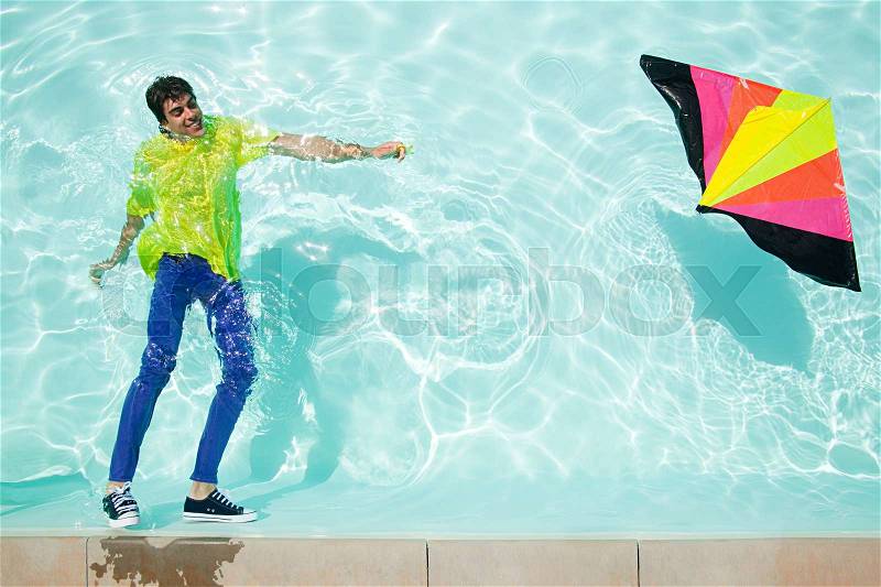 Man in pool with kite, stock photo