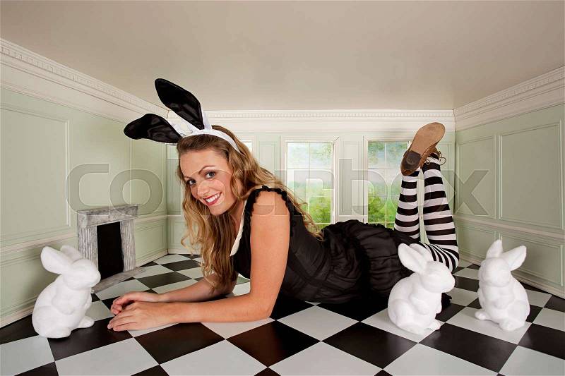 Young woman in small room with bunny ears and rabbit figures, stock photo