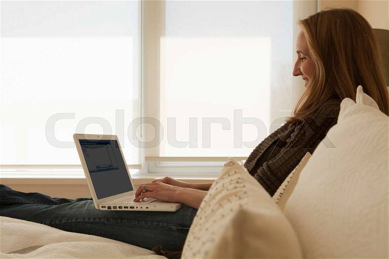 Woman working from home using laptop, stock photo