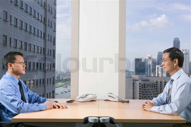 Businessmen sitting face to face, stock photo