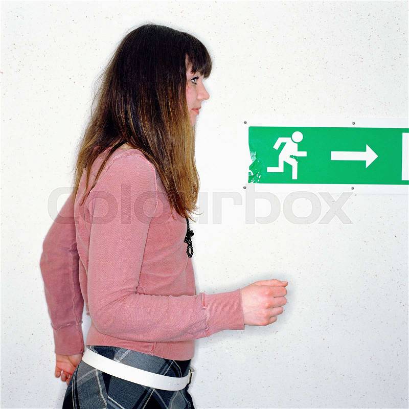 Girl walking past exit sign, stock photo