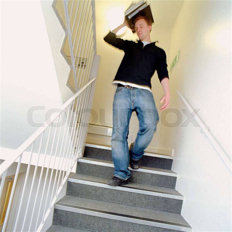 Student walking down the stairs holding folders, stock photo