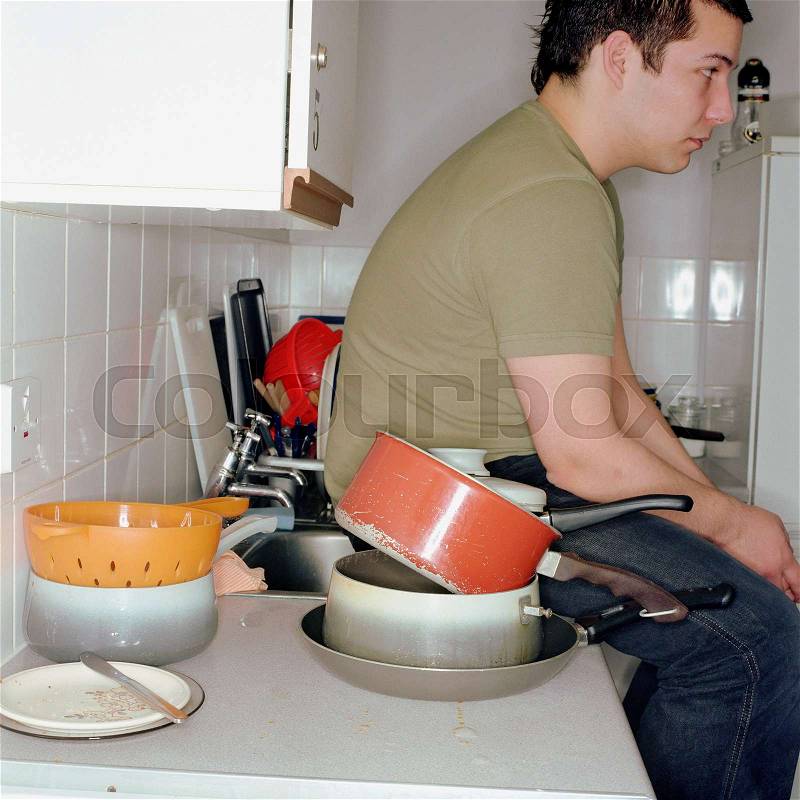 Boy sitting in a messy kitchen, stock photo
