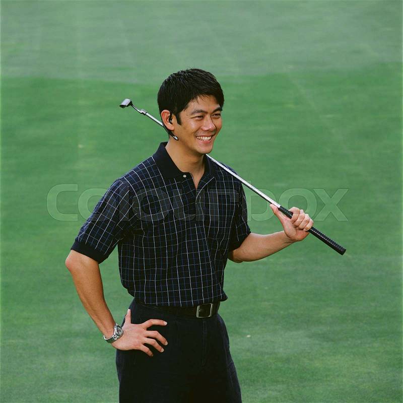 Man on golf green with bluetooth headset, stock photo