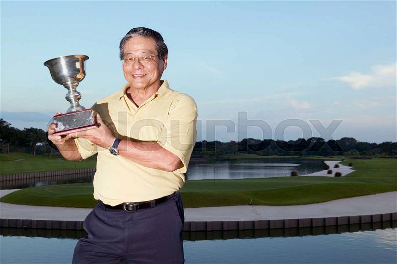 Male golfer holding trophy, stock photo