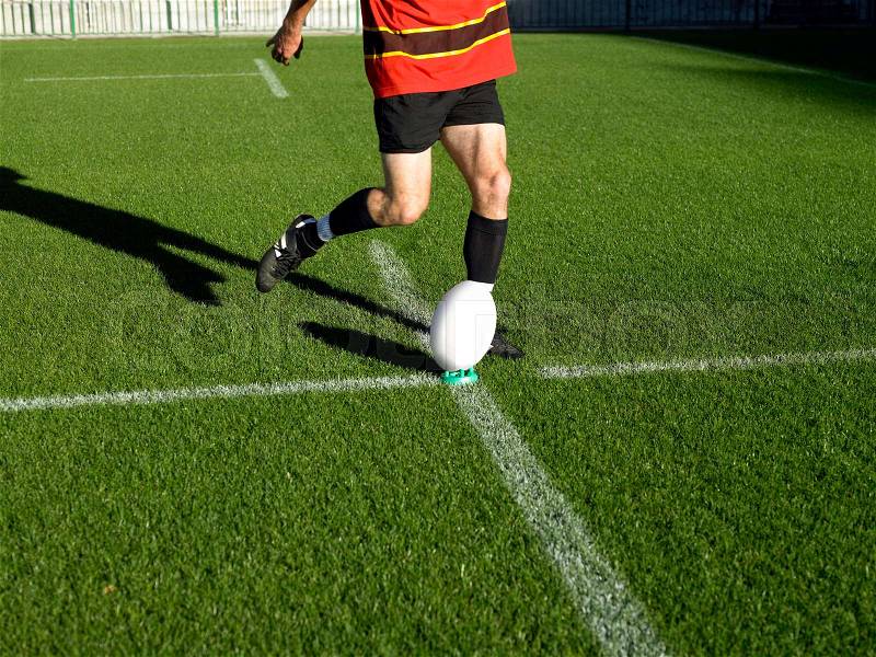 Rugby player kicking ball, stock photo