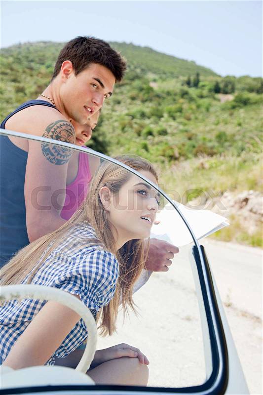 Young people with convertible car looking at map, stock photo