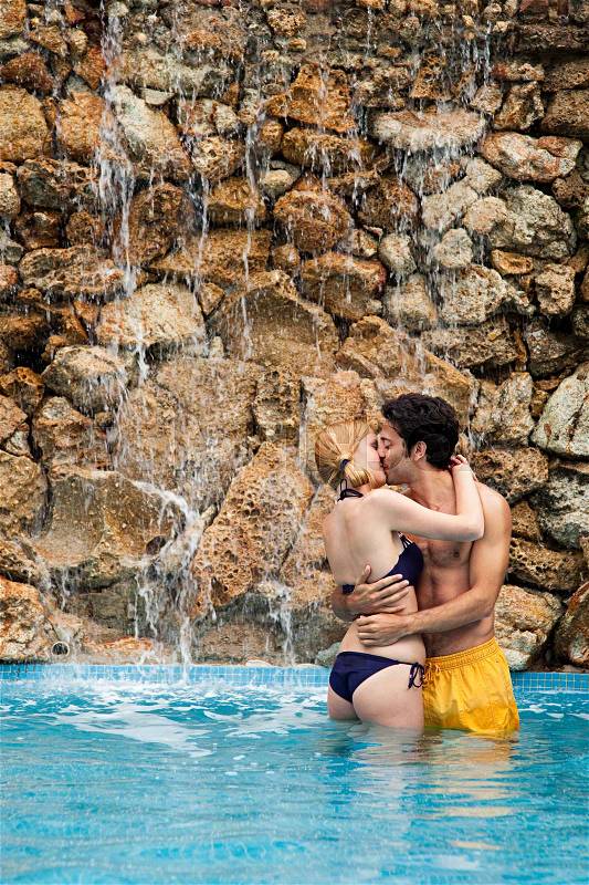Young couple embracing and kissing in swimming pool, stock photo