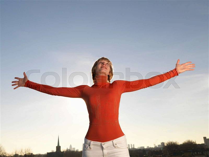 Woman standing, arms outstretched, stock photo