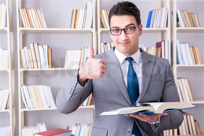 Business law student with magnifying glass reading a book, stock photo