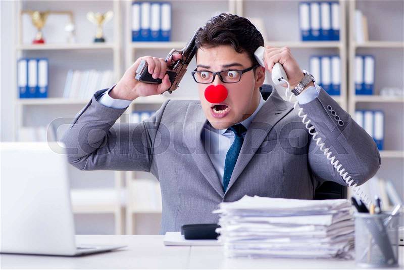 Clown businessman working in the office angry frustrated with a gun, stock photo