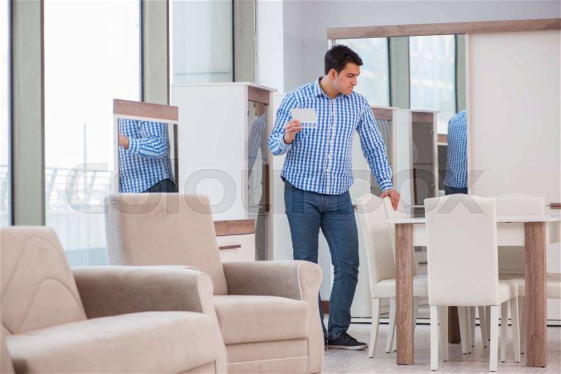 Young man shopping in furniture store, stock photo