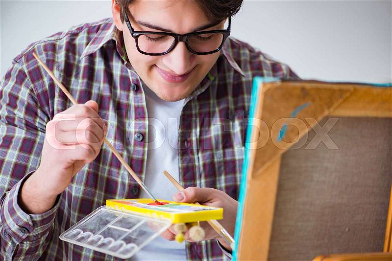 Young male artist drawing pictures in bright studio, stock photo