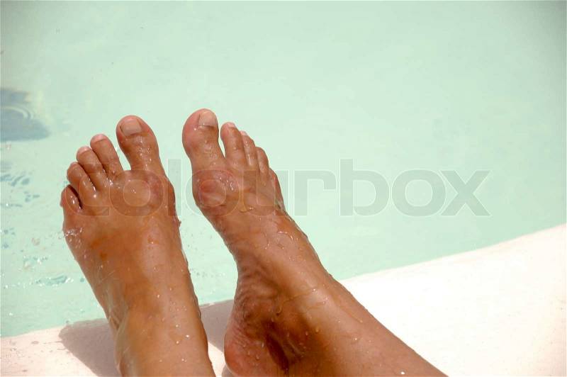 Feet by the pool side is being refreshed by cool water drops The water drops are in motion blur, stock photo